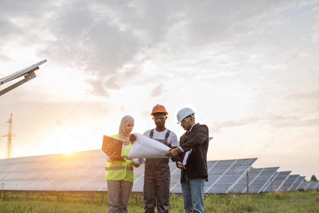 Multiracial people standing with blueprints on solar station