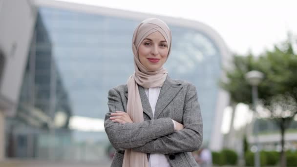 Femme musulmane dans le hijab, posant devant un bâtiment moderne et montrant pouce vers le haut. — Video
