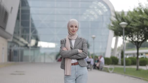 Femme musulmane, debout sur le fond du bâtiment moderne avec les bras croisés montrant un geste correct — Video