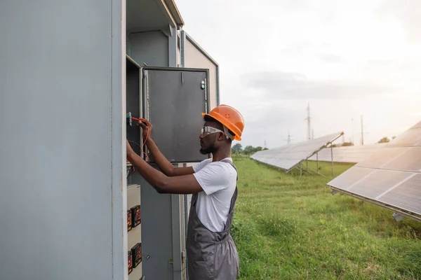 Afrykański elektryk wykonujący prace serwisowe na stacji słonecznej — Zdjęcie stockowe