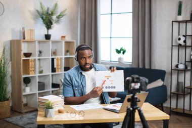 Kulaklık takmış Afrikalı Amerikalı bir adam online toplantı yapıyor.