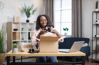 Yeni kablosuz kulaklıkla kutuları açan mutlu kadın.