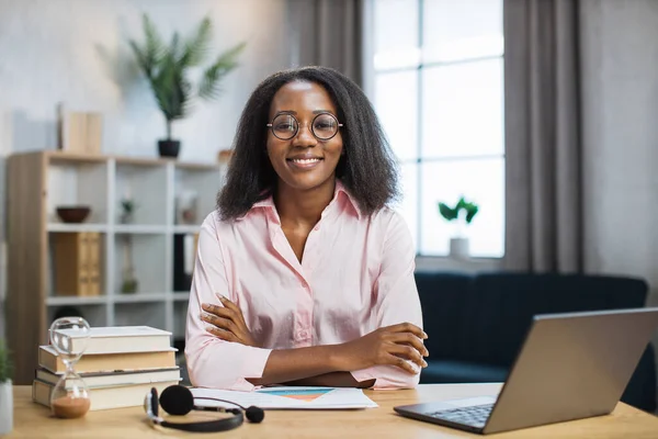 Vrouwelijke tutor in bril zittend aan bureau met boeken — Stockfoto