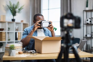 Afrikalı Amerikalı adam paket kutusunu açıyor ve video kaydediyor.