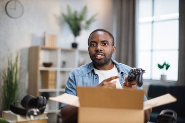 Afrikalı adam kumandayı açıp kamerayla konuşuyor.