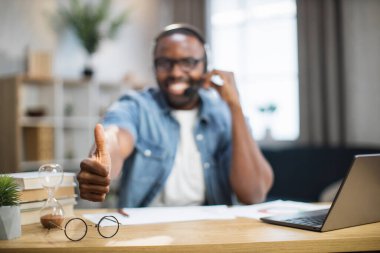 Kamerada baş parmağını gösteren kulaklıklı Afrikalı bir adam.