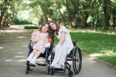 Tekerlekli sandalyedeki kadınlar yaz parkında eğleniyorlar.