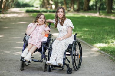 Tekerlekli sandalyedeki kadınlar yaz parkında eğleniyorlar.