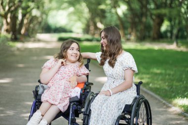 Tekerlekli sandalyedeki kadınlar yaz parkında eğleniyorlar.