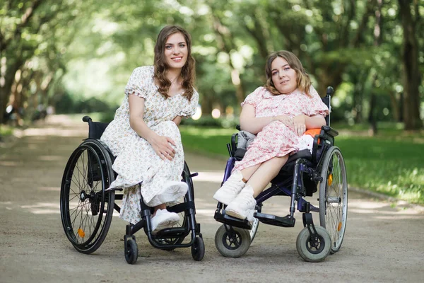 Δύο γυναίκες σε αναπηρικά καροτσάκια χαμογελούν μπροστά στην κάμερα στο πάρκο — Φωτογραφία Αρχείου
