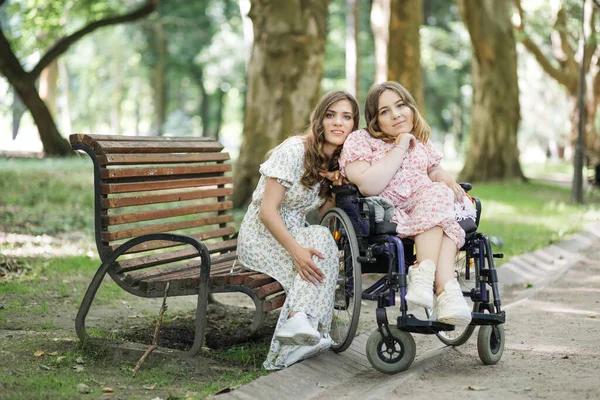 Γυναίκα σε αναπηρική καρέκλα και η γυναίκα φίλη της ποζάρουν στο πάρκο — Φωτογραφία Αρχείου