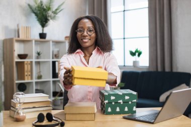 Gülümseyen Afrikalı etkileyici masada hediye kutuları açıyor