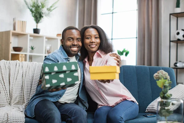 African couple holding gift boxes and smiling on camera — Stock Photo, Image