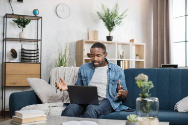 Mutlu Afro-Amerikalı adam dizüstü bilgisayarında video görüşmesi yapıyor.