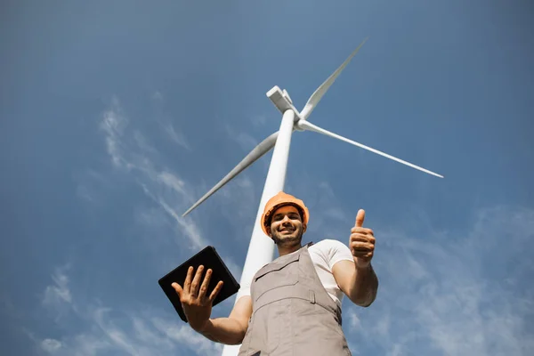 Mężczyzna za pomocą tabletu i pokazuje kciuk w pobliżu turbin wiatrowych — Zdjęcie stockowe
