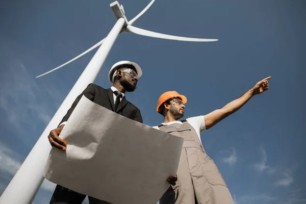 Inspektor i inżynier rozmawiający na polu z turbinami wiatrowymi — Zdjęcie stockowe