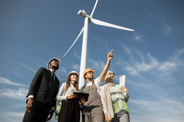 Partnerzy wielokulturowi badający pracę turbin wiatrowych — Zdjęcie stockowe