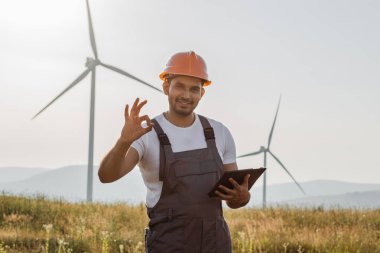 Yel değirmenleriyle sahada dikilen adam işaret veriyor.