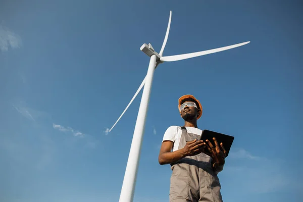 Technician using tablet for work on farm with wind turbines — Zdjęcie stockowe