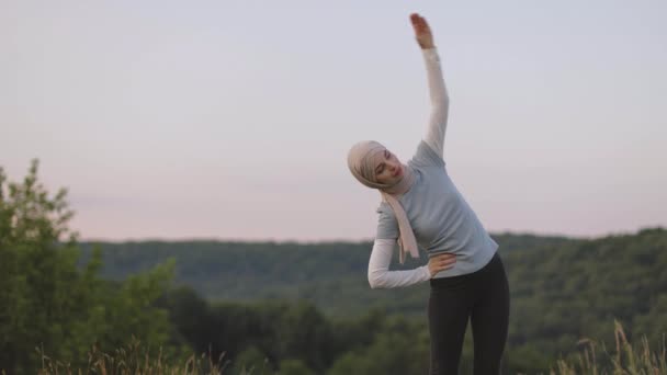 Portret van moslim vrouw gekleed in religieuze beige hijab strekken haar handen tijdens het doen van training — Stockvideo