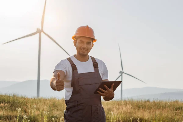 Man showing sign ok while standing on field with windmills — 图库照片