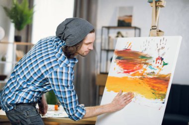 Inspired man drawing colorful pattern with hands on easel