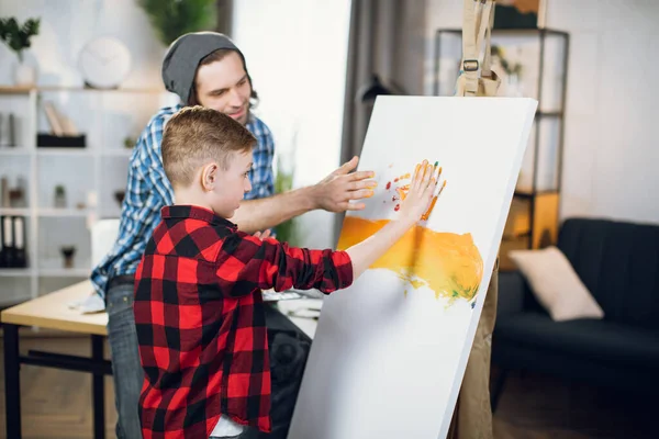 Father and son drawing with hands on canvas — Stockfoto