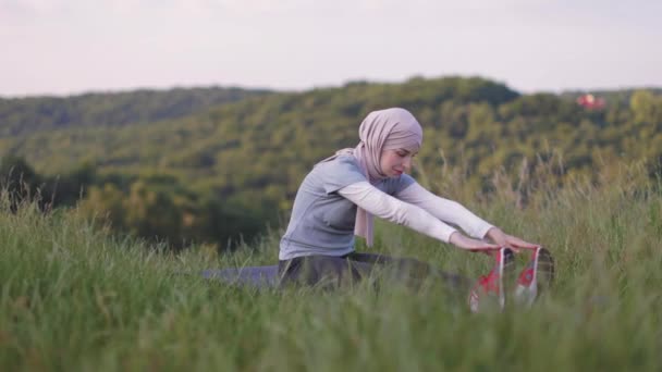 Frau im Hidschab streckt Körper im Sommerpark — Stockvideo