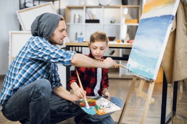 Teacher and boy using brushes and palette for drawing