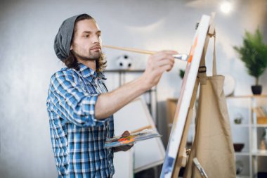 Inspired artist using color palette and brush for painting