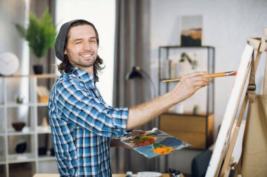 Male artist winking and smiling on camera while drawing