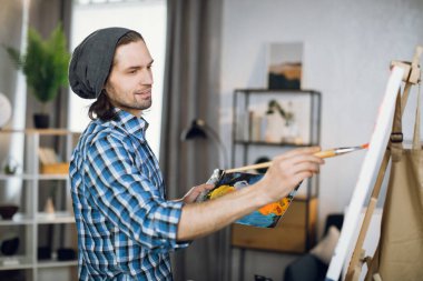 Man drawing with brush on canvas at art studio
