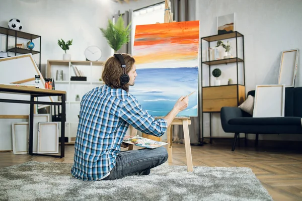 Artist in headset listening music and drawing on canvas —  Fotos de Stock