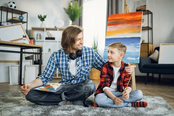 Father embracing son while resting on floor after painting — Foto de Stock