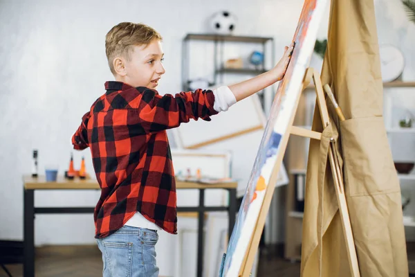 Niño inspirado creando su obra maestra en caballete con las manos — Foto de Stock