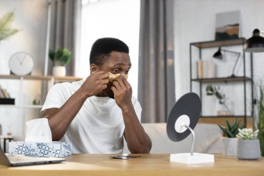 Sporty happy African guy applying golden patches under his eyes