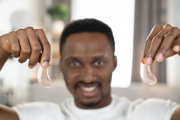 Blur view of African man in white T-shirt holding collagen patches in his hands. — Stock Photo, Image