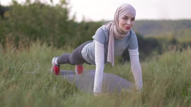 Portrait of attractive young Muslim woman smiling and doing plank. — Stock video