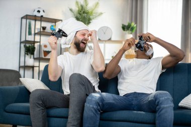 Çok ırklı erkekler cilt bakımı prosedürleri yapıyor, joysticklerle video oyunları oynuyorlar.