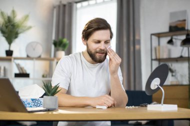 Beyaz adam hijyenik prosedürler uyguluyor, yüzünü pamukla temizliyor.