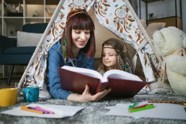 Anne ve kızı oyuncak çadırında kitap okuyorlar. — Stok fotoğraf