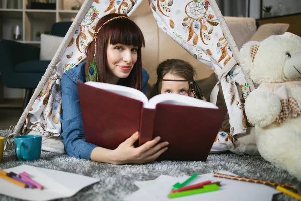 Kadın ve çocuk çadırda uzanıp kitap okuyorlar. — Stok fotoğraf