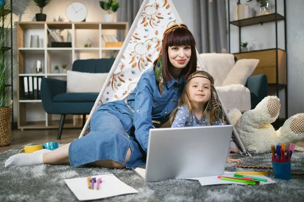 Vrouw en kind zitten in de buurt tipi en met behulp van laptop — Stockfoto
