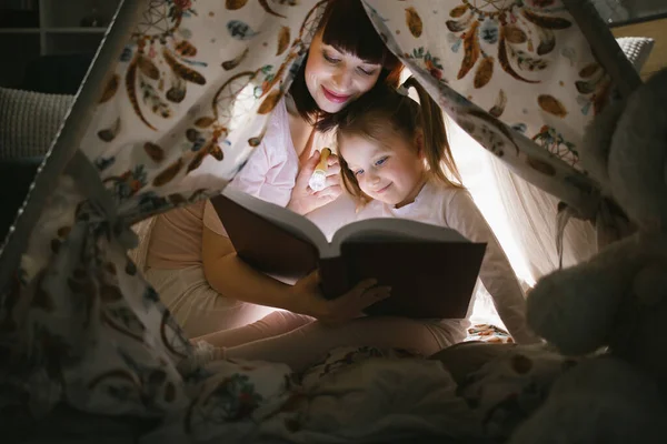 Moeder lezen boek met dochter in wigwam 's nachts — Stockfoto