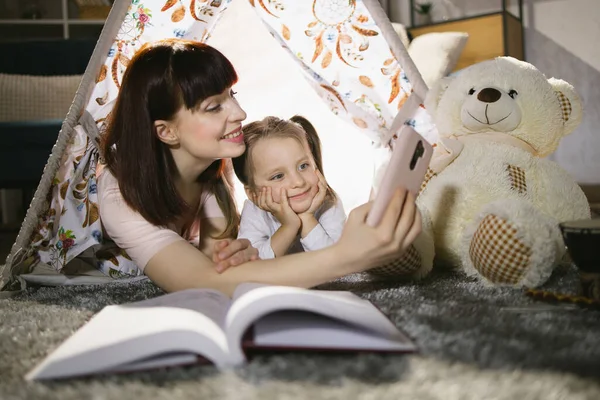 Moeder en dochter nemen selfie op mobiele binnen wigwam — Stockfoto