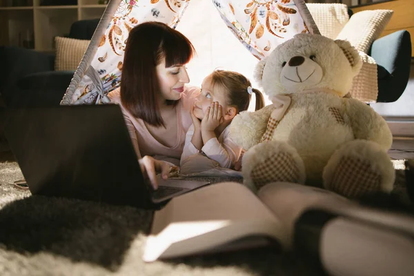 Moeder en dochter met behulp van laptop tijdens het spelen in wigwam — Stockfoto