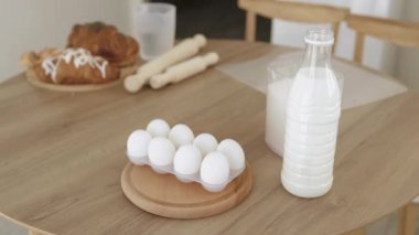 Plastik şişedeki süt, yumurta ve un ahşap bir masada yatıyor.