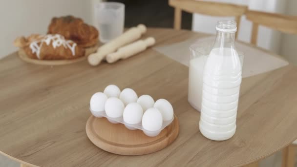 Melk in een plastic fles, eieren en bloem liggen op een houten tafel — Stockvideo