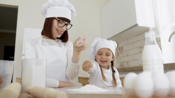 Overjoyed mom have fun sprinkling flour and baking cookies or pastries with cute preschooler girl — Stock Video