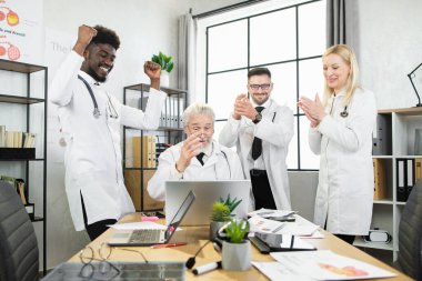 Konferans sırasında gülümseyen ve alkışlayan çok kültürlü doktorlar.